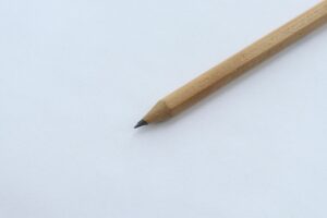 Minimalist close-up of a wooden pencil on white paper, highlighting simplicity and creativity.
