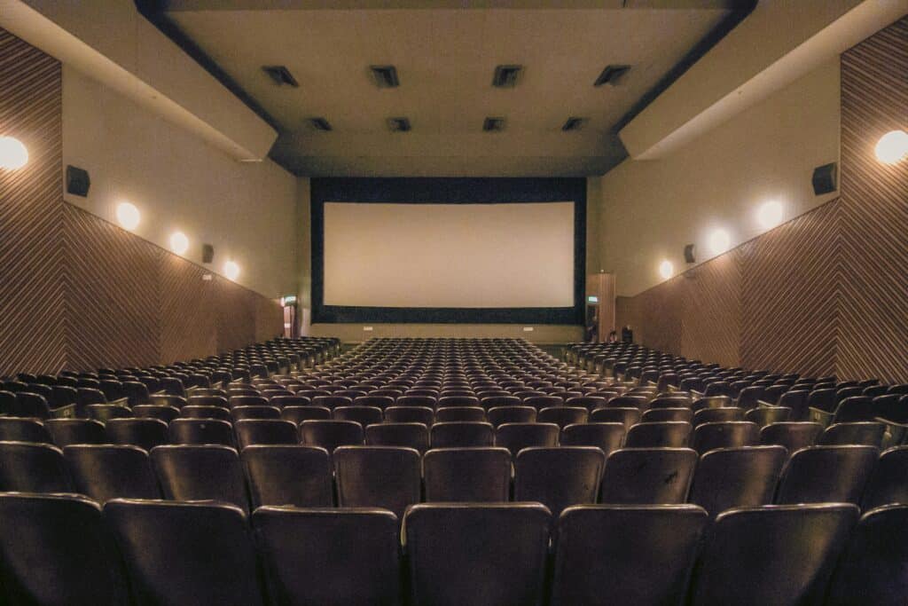 A vacant theater showing rows of seats and a large screen.